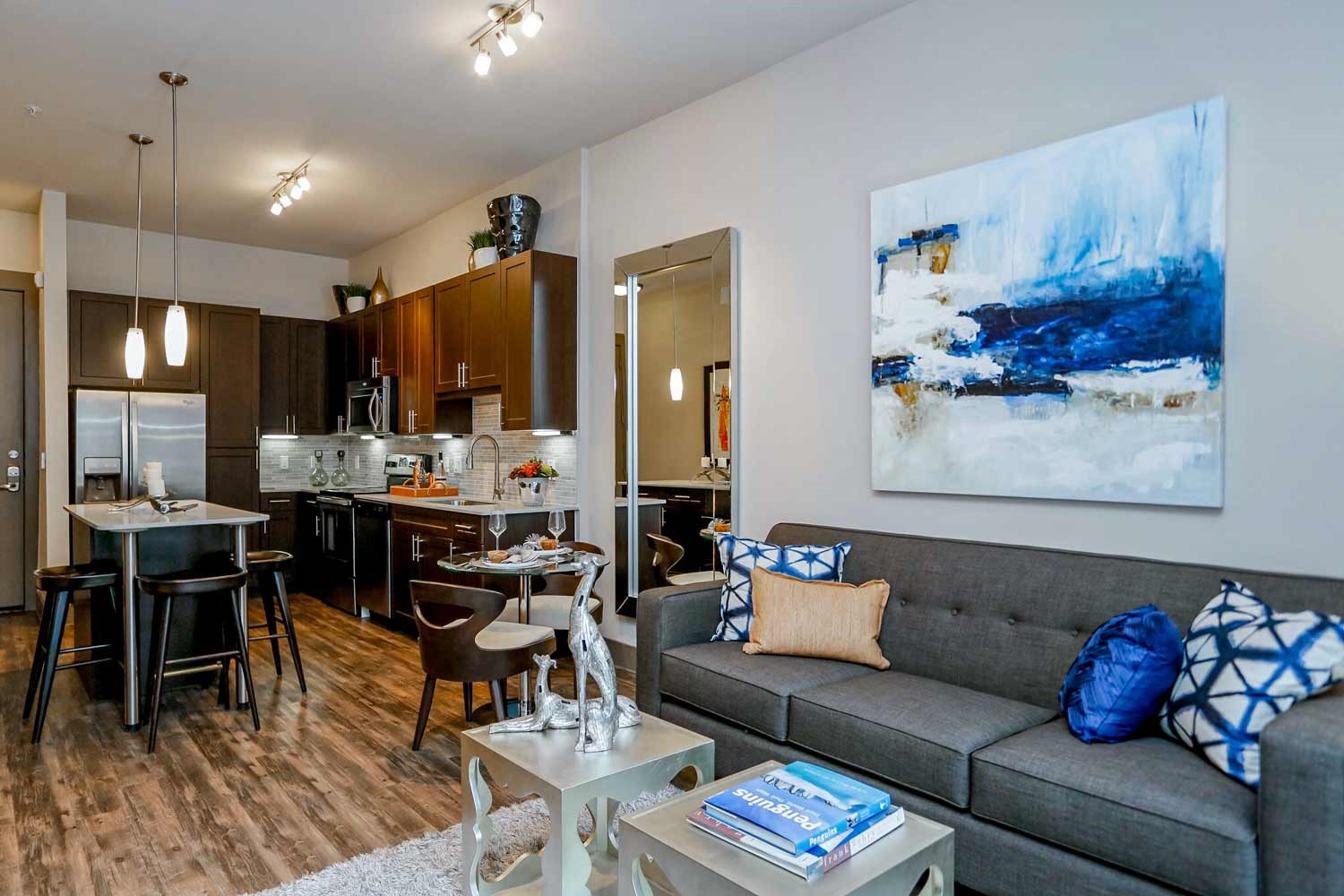 a living room with furniture kitchen view and a wooden floor