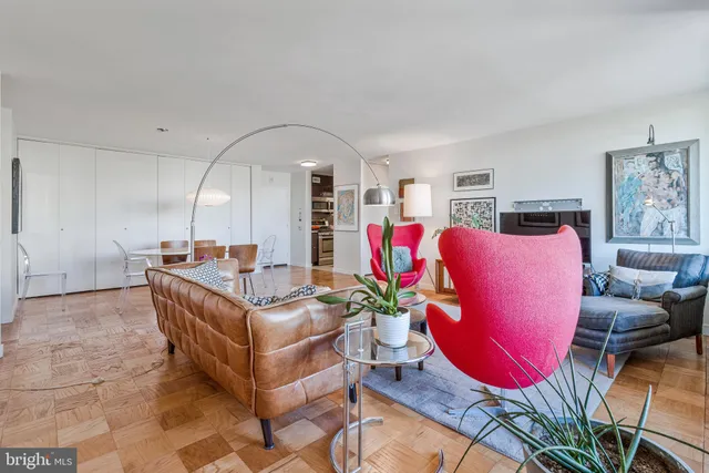 a living room with furniture a rug kitchen view and a large window
