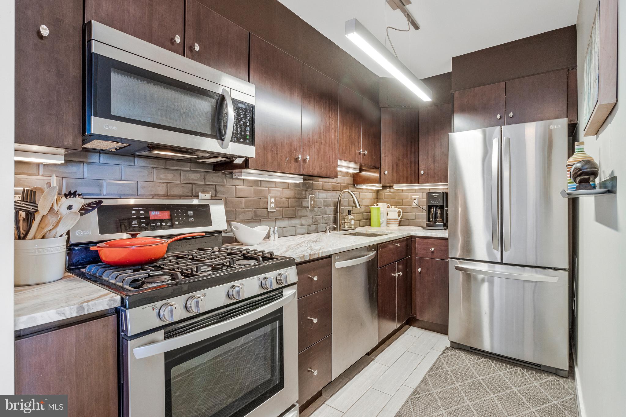 1245 4th Street Southwest, Unit E501 Washington, DC 20024 - Photo 16 of 40 a kitchen with stainless steel appliances granite countertop a stove microwave refrigerator and sink