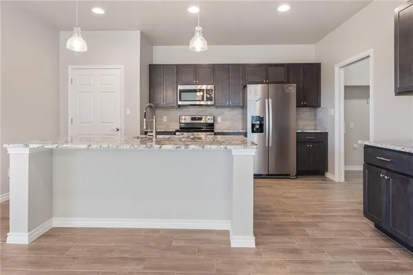 a view of kitchen with granite countertop cabinets and refrigerator