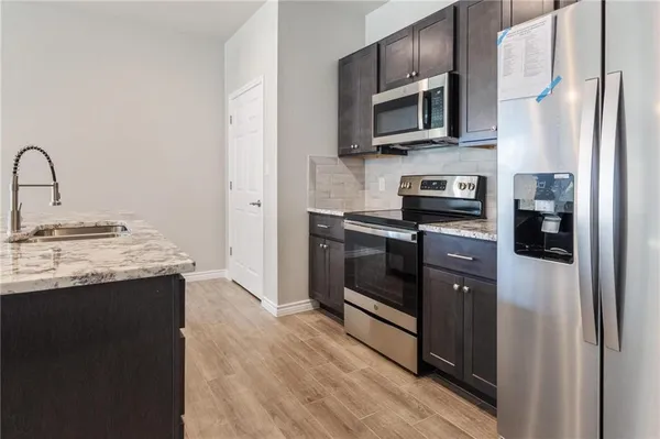 a kitchen with stainless steel appliances granite countertop a refrigerator a sink a stove and oven