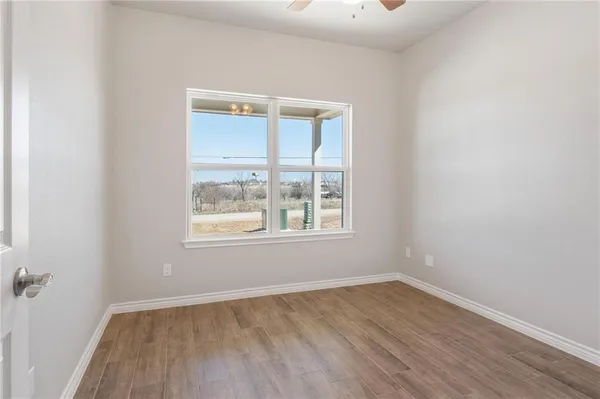 a view of empty room with wooden floor and fan