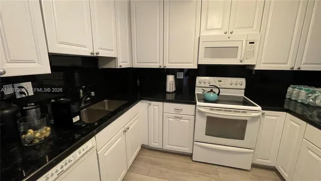 a kitchen with granite countertop white cabinets and sink