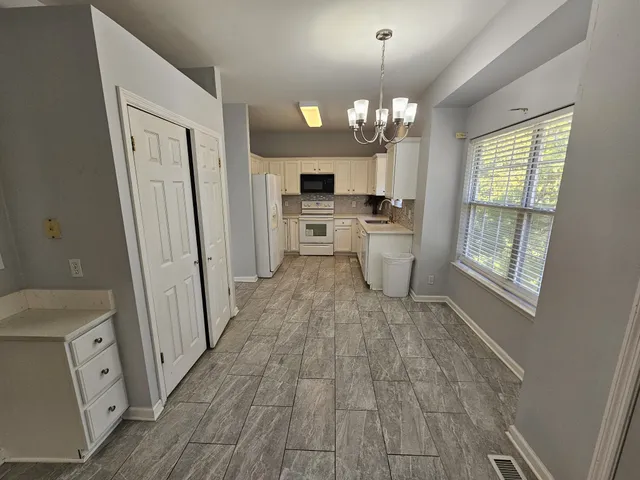 a view of a kitchen with a sink wooden floor and chandelier