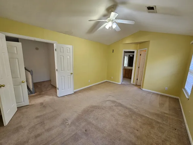 an empty room with a chandelier fan and windows