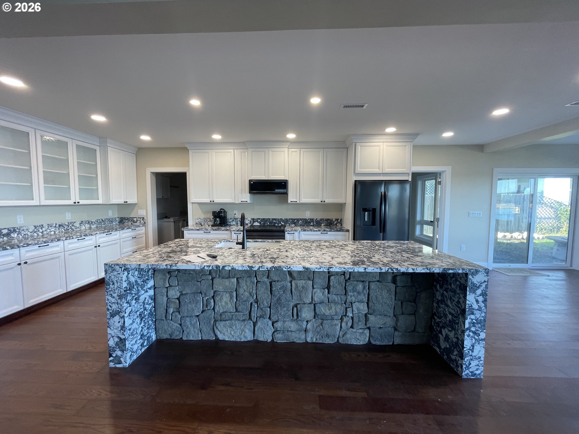 360 2nd Street Southeast Bandon, OR 97411 - Photo 26 of 28 a kitchen with kitchen island granite countertop wooden cabinets and a sink