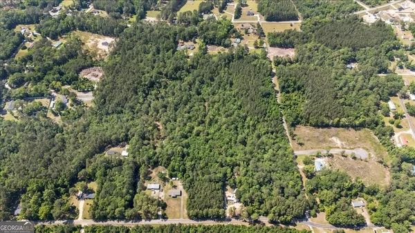 an aerial view of residential houses with outdoor space and trees