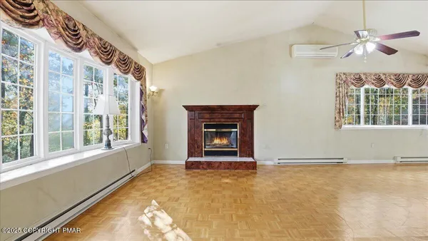 a view of an empty room with a window and wooden floor