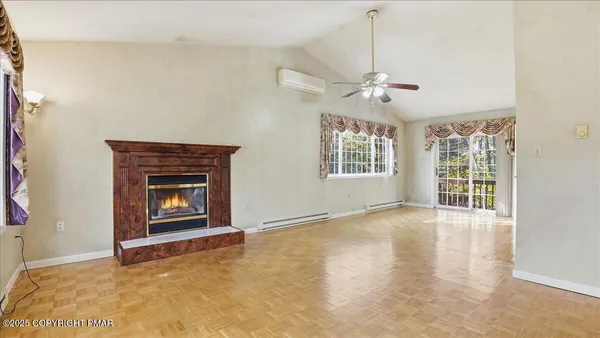a view of an empty room with window and wooden floor