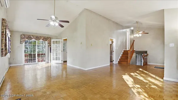 an empty room with wooden floor fan and windows