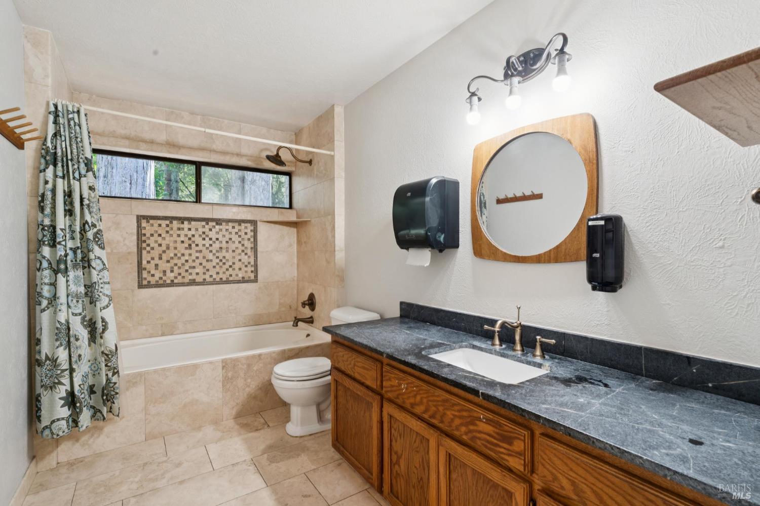 11910 Graton Road Sebastopol, CA 95472 - Photo 57 of 81 a spacious bathroom with a granite countertop sink a mirror a toilet and a bathtub