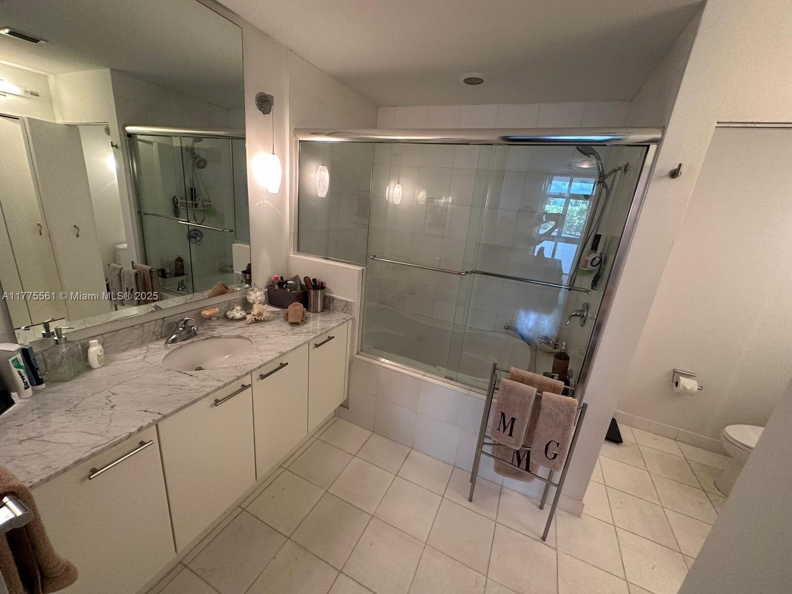 2001 Meridian Avenue, Unit 309 Miami Beach, FL 33139 - Photo 14 of 21 a spacious bathroom with a double vanity sink a toilet a mirror and shower