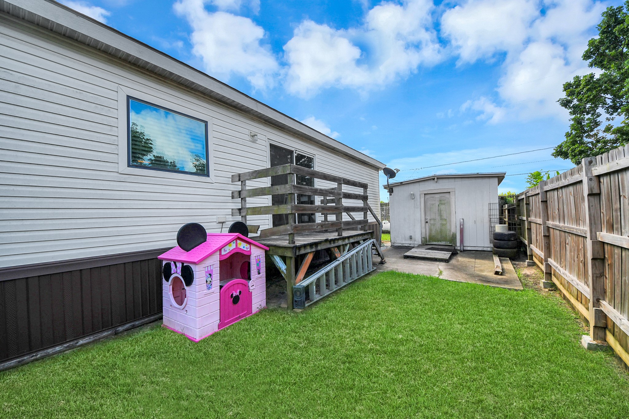 131 Kiowa Court Rosharon, TX 77583 - Photo 31 of 42 A fenced backyard with a well-maintained lawn, a wooden deck, and a small storage shed.
