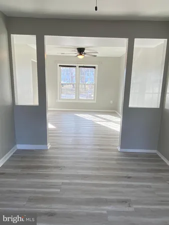 a view of an empty room with window and wooden floor