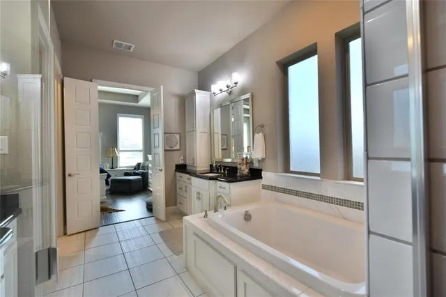 a bathroom with a tub a sink and a large mirror