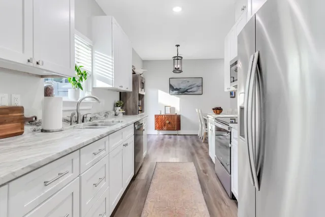 a kitchen with stainless steel appliances a refrigerator sink and white cabinets