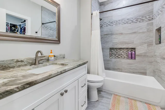 a bathroom with a granite countertop sink a toilet and bathtub