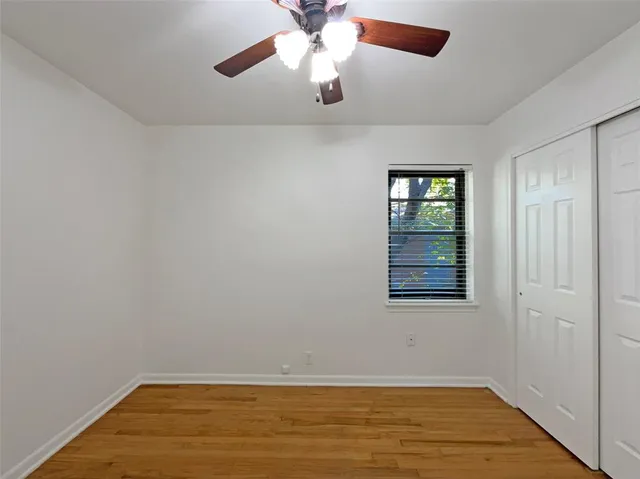 an empty room with a window and ceiling fan