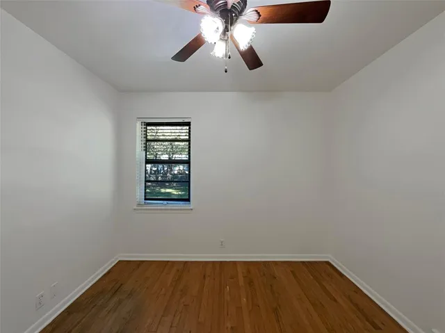 an empty room with a window and a chandelier fan