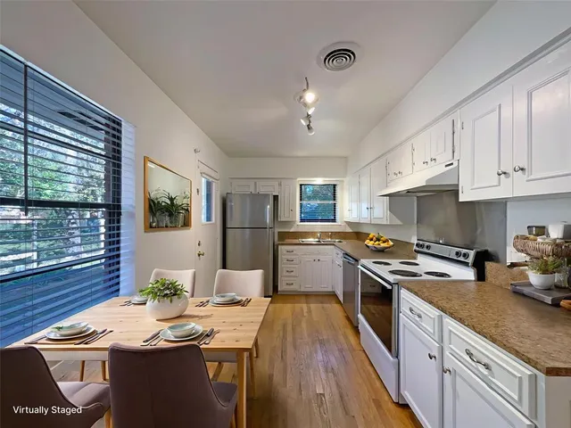 a kitchen with stainless steel appliances granite countertop a stove a sink dishwasher a microwave oven and a dining table with wooden floor
