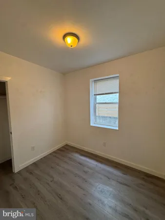 an empty room with wooden floor and fan