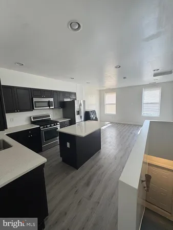 a kitchen with stainless steel appliances a stove a sink a refrigerator white cabinets and wooden floor