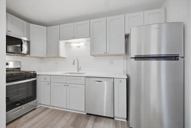a white refrigerator freezer sitting inside of a kitchen with stainless steel appliances granite countertop wooden cabinets and a stove