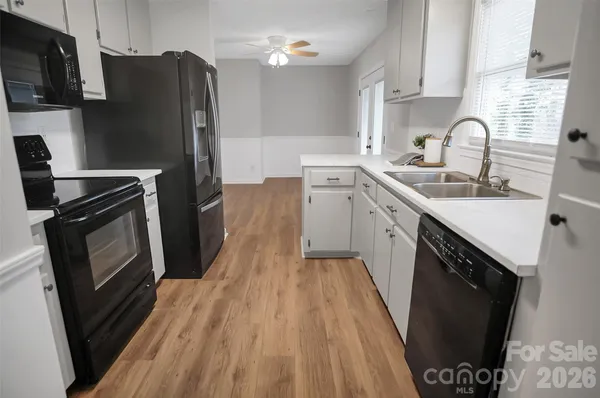 a kitchen with granite countertop a refrigerator a sink dishwasher stove and wooden cabinets