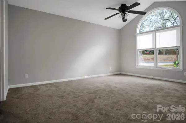 an empty room with windows and ceiling fan