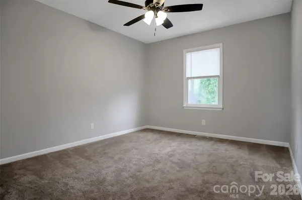 an empty room with a window and a fan