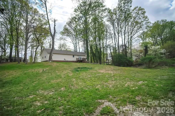 a view of a white house in front of a big yard with large trees