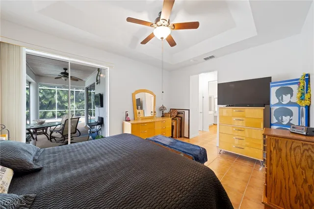 a bedroom with a bed a chandelier and flat screen tv