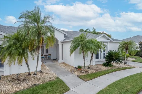 a palm tree sitting in front of a house with a yard