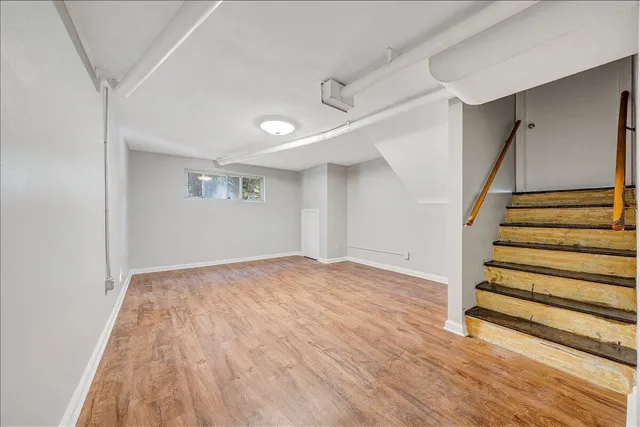 a view of an empty room with stairs and wooden floor
