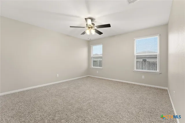 an empty room with chandelier fan and windows