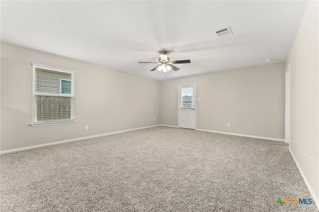 an empty room with windows and chandelier fan
