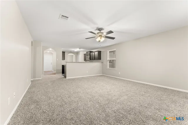 an empty room with windows and ceiling fan