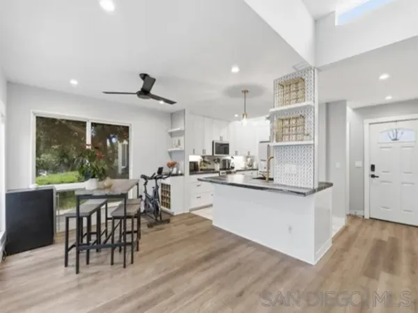 a kitchen with stainless steel appliances kitchen island granite countertop a table chairs sink and cabinets
