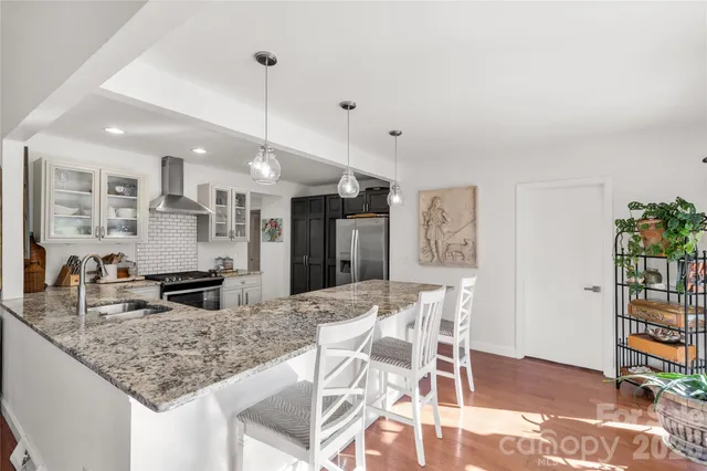 a kitchen with granite countertop kitchen island stainless steel appliances a table and chairs in it