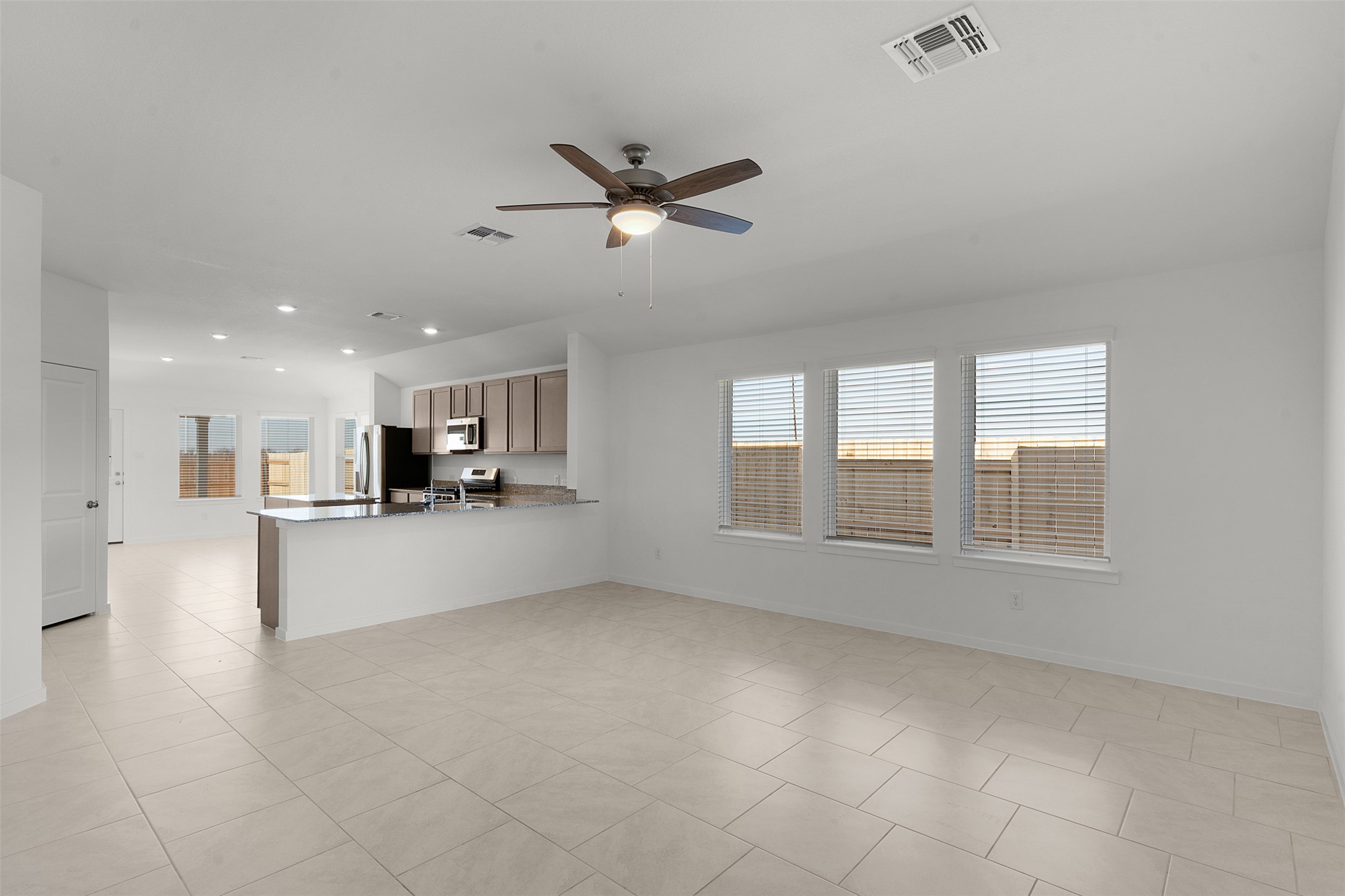 13832 Scarlett Song Drive Elgin, TX 78621 - Photo 6 of 26 Unfurnished living room with ceiling fan, plenty of natural light, light tile patterned floors, and recessed lighting