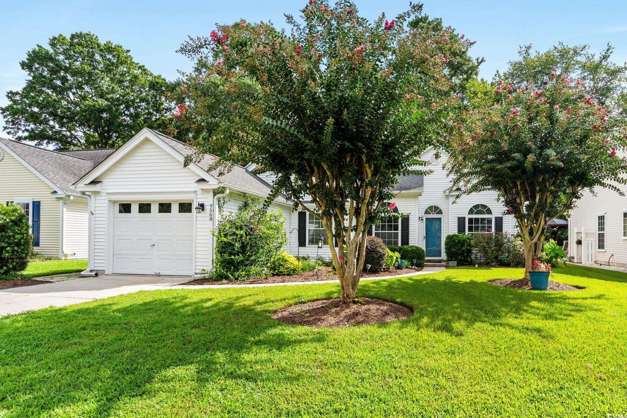 View of front of home featuring a front yard, a garage, driveway, and a shingled roof