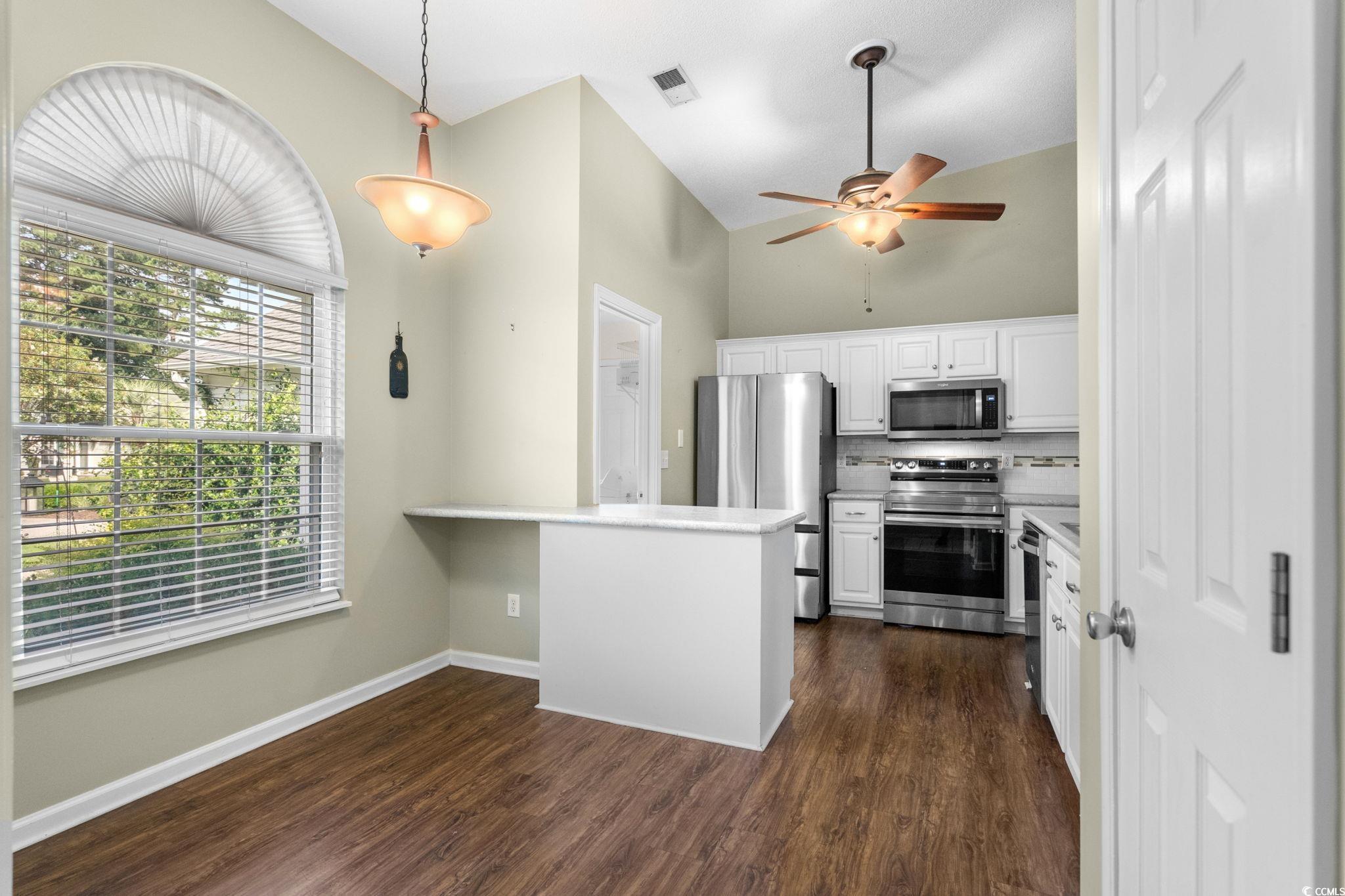 9568 Indigo Club Drive Murrells Inlet, SC 29576 - Photo 11 of 40 Kitchen with appliances with stainless steel finishes, hanging light fixtures, white cabinetry, dark wood-style flooring, and a peninsula