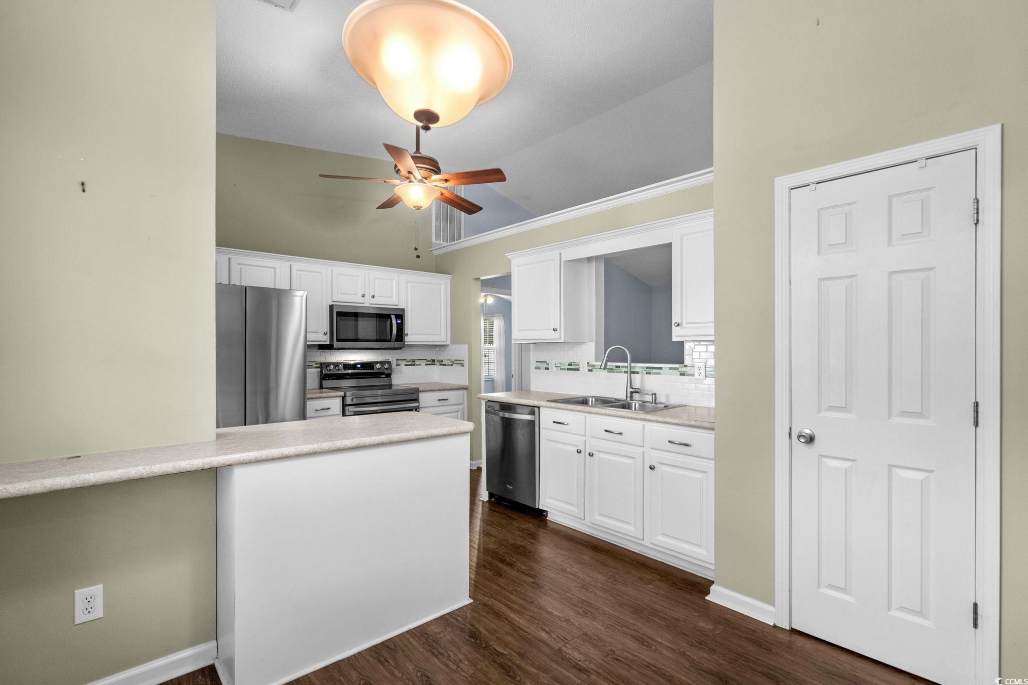 9568 Indigo Club Drive Murrells Inlet, SC 29576 - Photo 14 of 40 Kitchen with tasteful backsplash, light countertops, crown molding, stainless steel appliances, and white cabinets