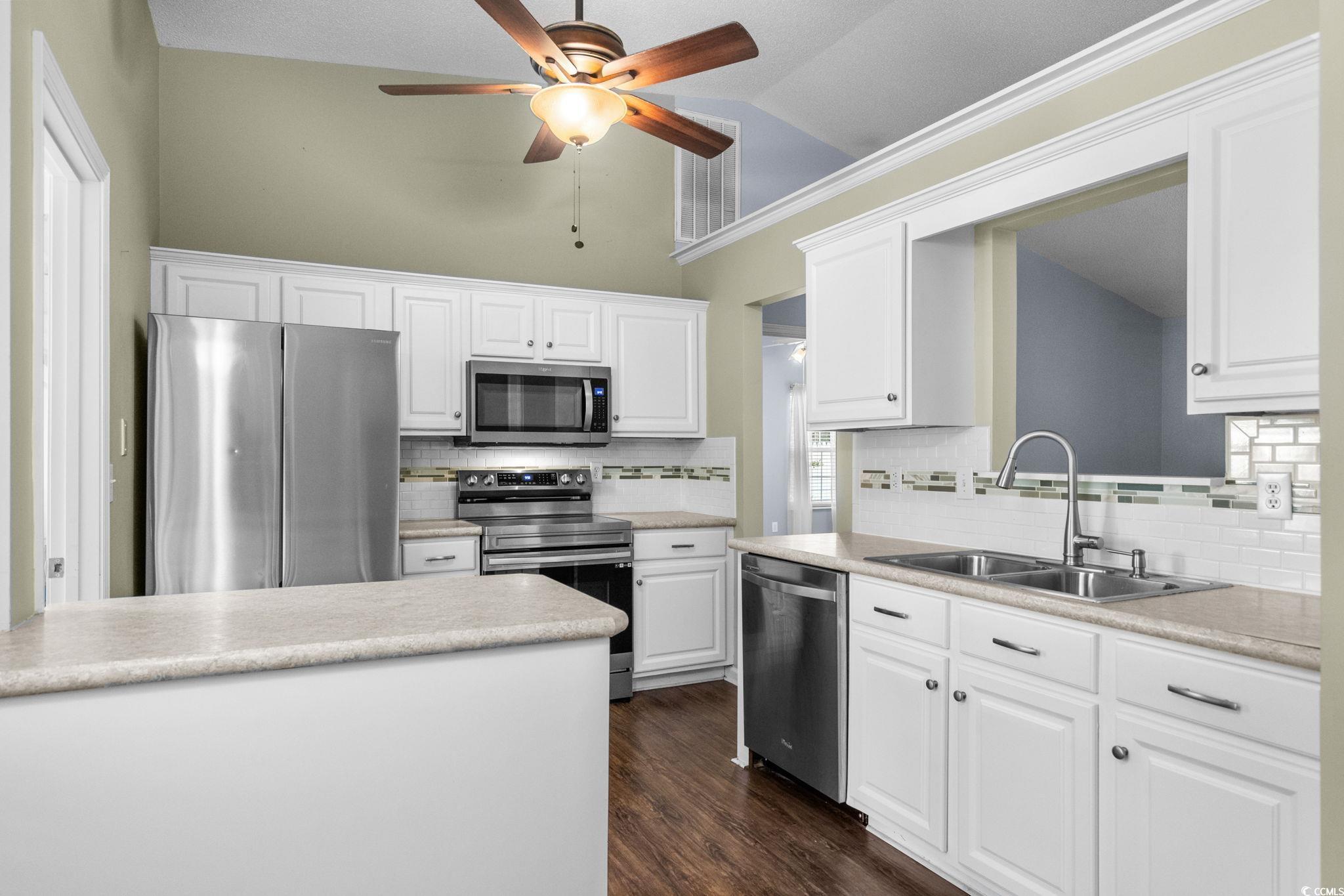 9568 Indigo Club Drive Murrells Inlet, SC 29576 - Photo 15 of 40 Kitchen with appliances with stainless steel finishes, light countertops, lofted ceiling, tasteful backsplash, and white cabinetry