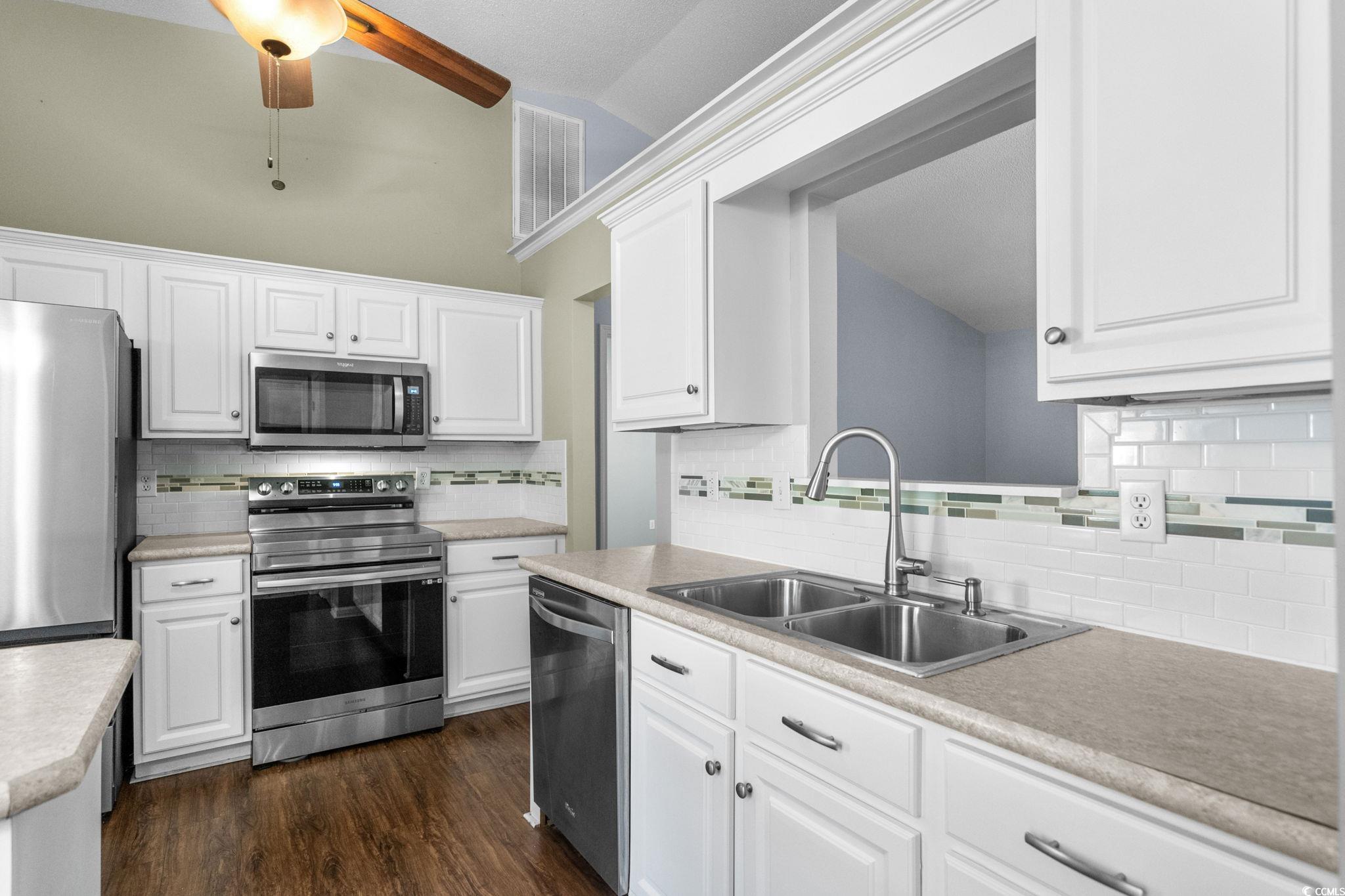 9568 Indigo Club Drive Murrells Inlet, SC 29576 - Photo 16 of 40 Kitchen featuring appliances with stainless steel finishes, white cabinetry, decorative backsplash, light countertops, and high vaulted ceiling