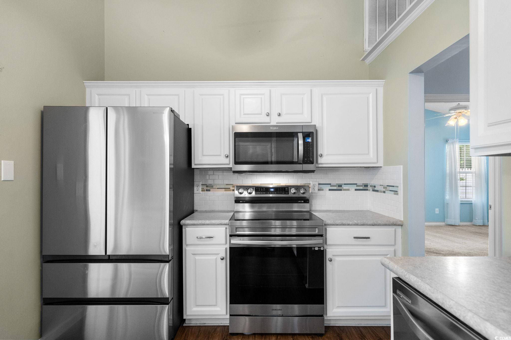 9568 Indigo Club Drive Murrells Inlet, SC 29576 - Photo 17 of 40 Kitchen with appliances with stainless steel finishes, white cabinetry, backsplash, and dark wood-type flooring