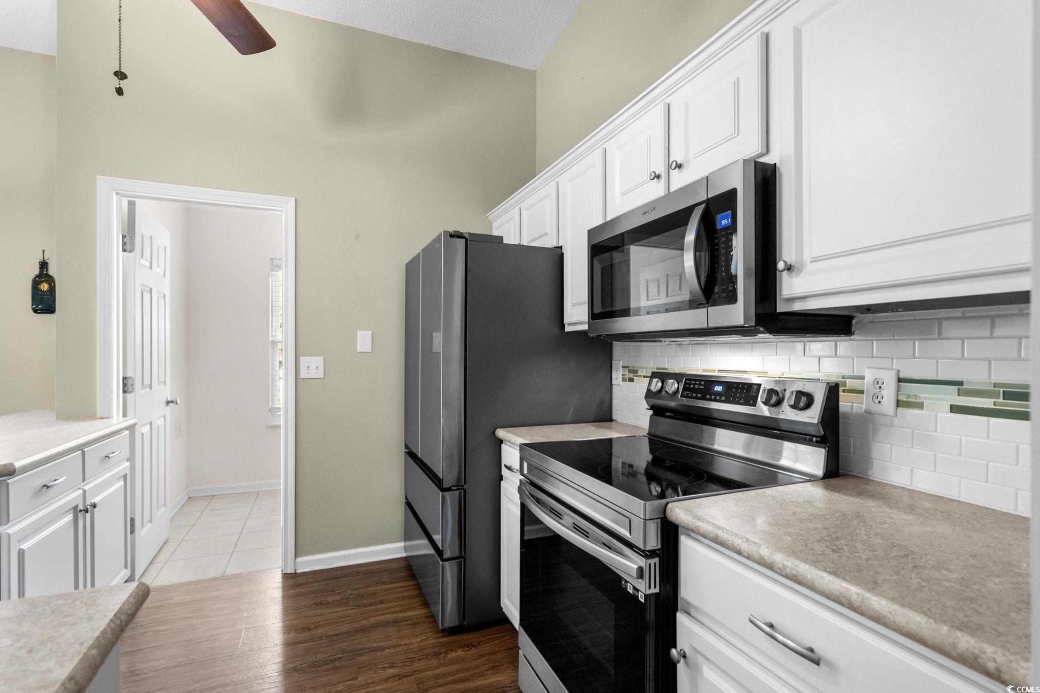 9568 Indigo Club Drive Murrells Inlet, SC 29576 - Photo 18 of 40 Kitchen featuring stainless steel appliances, tasteful backsplash, white cabinets, dark wood-type flooring, and light countertops
