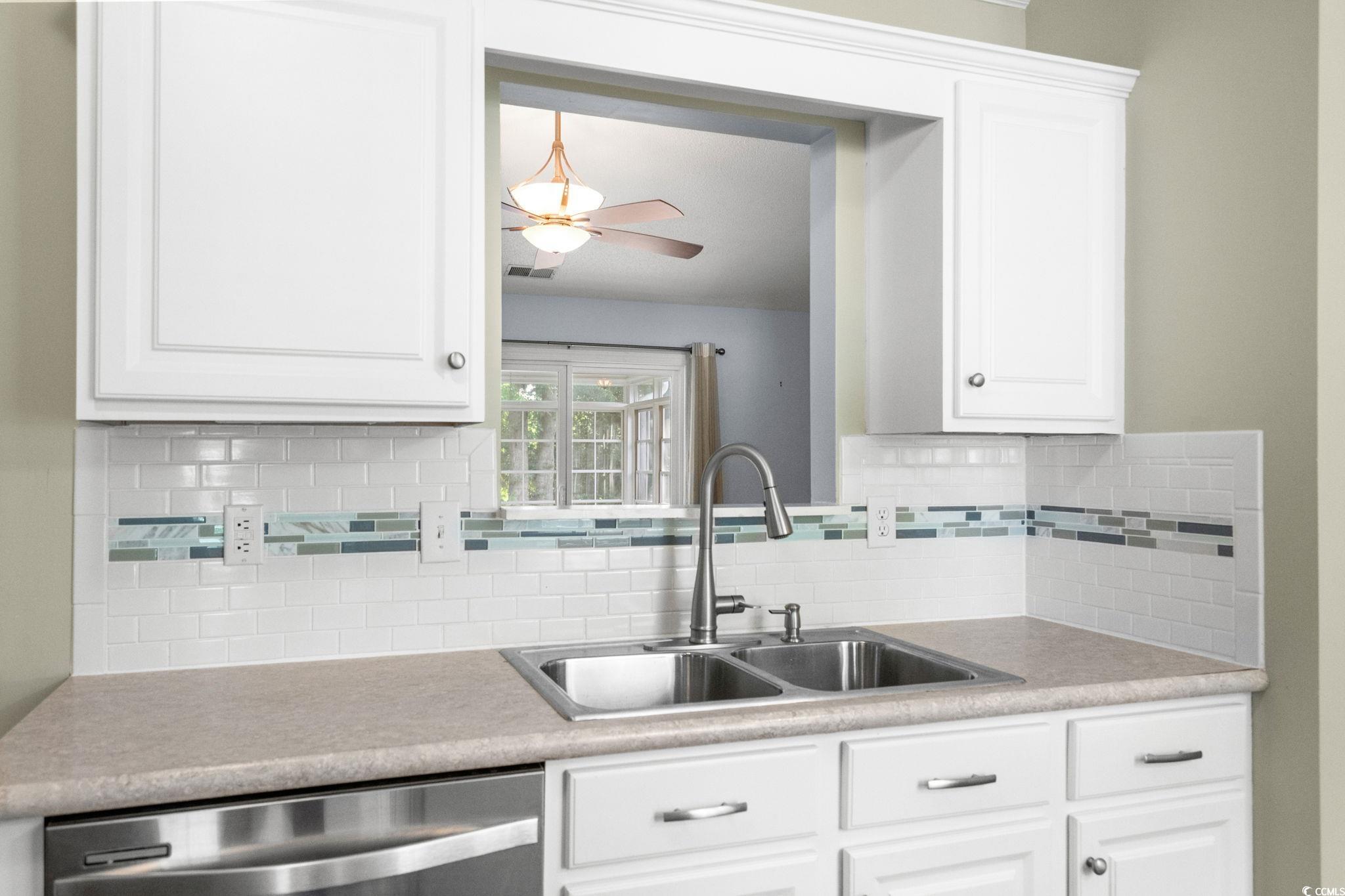 9568 Indigo Club Drive Murrells Inlet, SC 29576 - Photo 20 of 40 Kitchen featuring white cabinets, stainless steel dishwasher, light countertops, and decorative backsplash