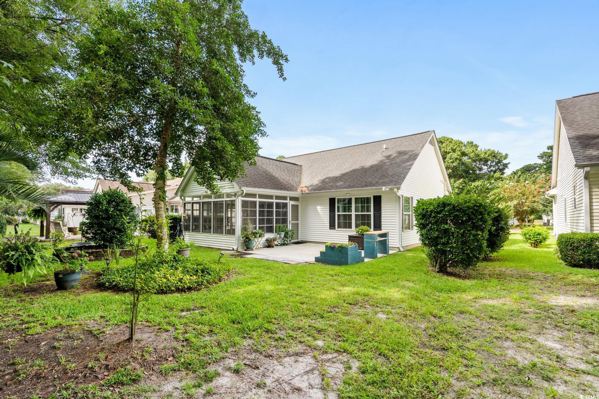 9568 Indigo Club Drive Murrells Inlet, SC 29576 - Photo 36 of 40 Back of house with a patio area, a sunroom, a yard, and a shingled roof