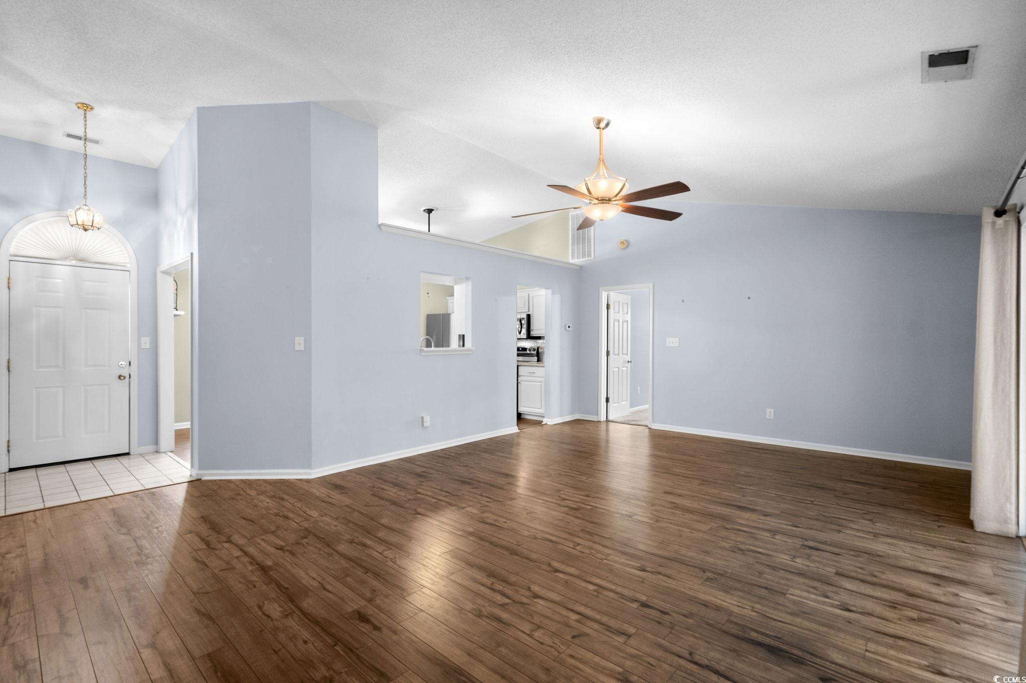9568 Indigo Club Drive Murrells Inlet, SC 29576 - Photo 8 of 40 Unfurnished living room featuring dark wood-style flooring, vaulted ceiling, and ceiling fan